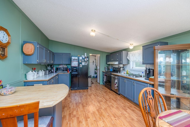 kitchen with sink, light hardwood / wood-style flooring, a textured ceiling, and appliances with stainless steel finishes