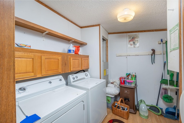 laundry area featuring cabinets, a textured ceiling, crown molding, wood-type flooring, and independent washer and dryer