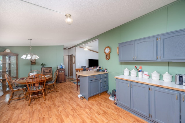 kitchen with hanging light fixtures, light hardwood / wood-style flooring, blue cabinets, a textured ceiling, and lofted ceiling