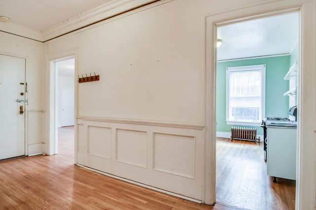 hall with crown molding, radiator heating unit, and light wood-type flooring