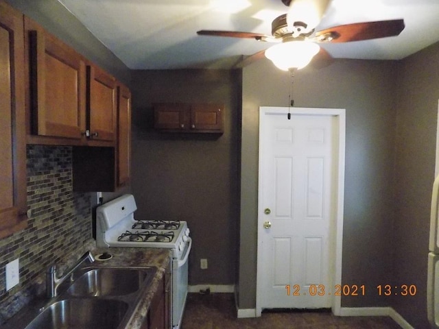 kitchen with ceiling fan, white gas range, sink, and tasteful backsplash