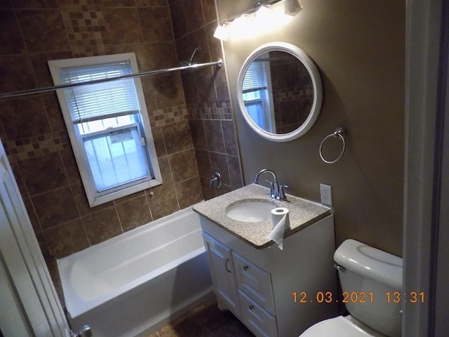 full bathroom featuring tiled shower / bath, vanity, and toilet