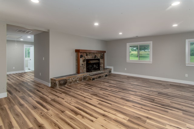 living room featuring hardwood / wood-style floors, a stone fireplace, and a wealth of natural light