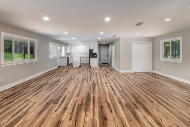 unfurnished living room with light wood-type flooring and sink