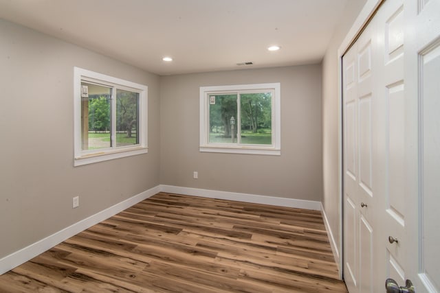 unfurnished bedroom featuring wood-type flooring, a closet, and multiple windows