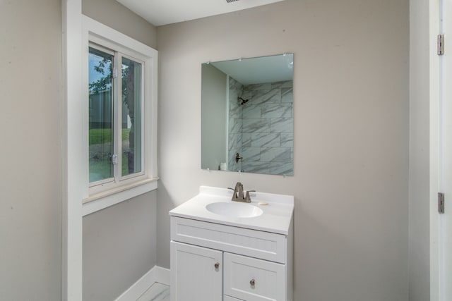 bathroom with plenty of natural light, tiled shower, and vanity