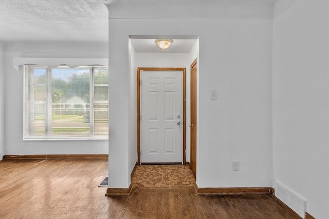 foyer entrance featuring hardwood / wood-style floors, plenty of natural light, and a textured ceiling