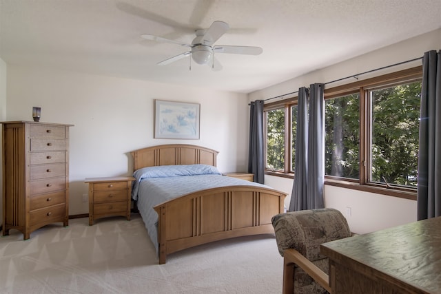 bedroom with a textured ceiling, ceiling fan, and light carpet