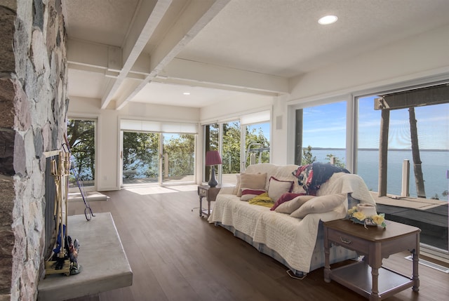 sunroom / solarium featuring beamed ceiling, plenty of natural light, and a water view