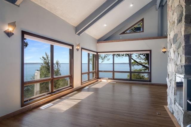 living room with a fireplace, a water view, wood-type flooring, and high vaulted ceiling