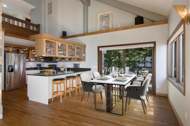 dining space featuring wood-type flooring and high vaulted ceiling