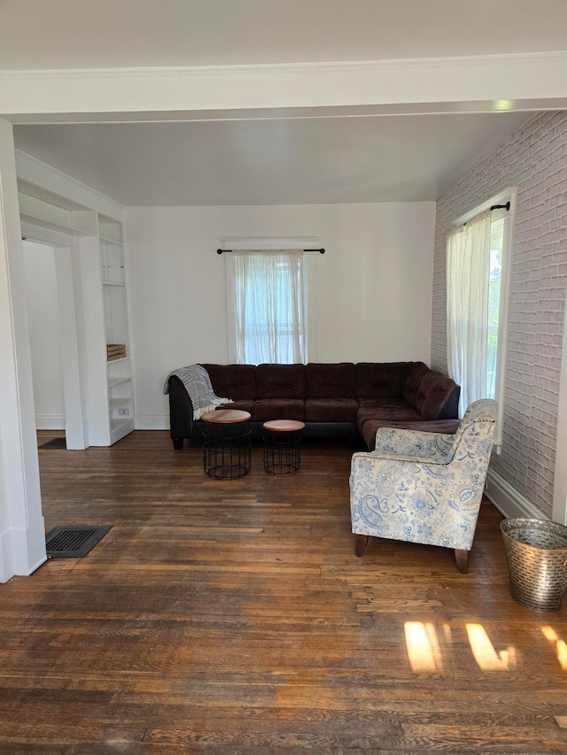 living room with dark wood-type flooring and brick wall