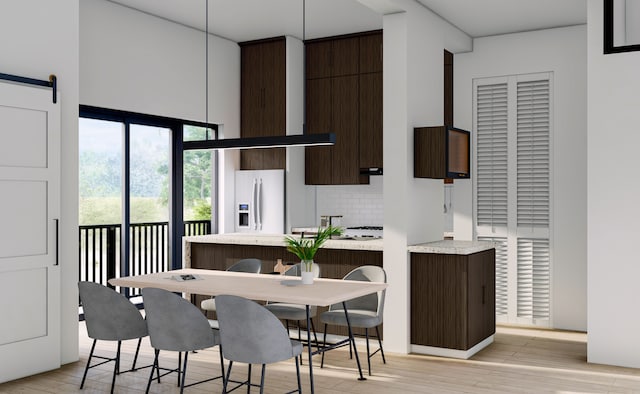 dining area featuring light wood-type flooring and a barn door