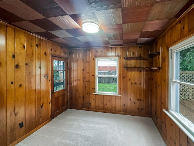 carpeted spare room with wood walls and wood ceiling