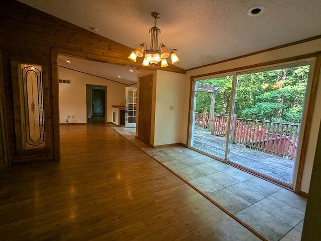 entryway with a chandelier, wood-type flooring, a textured ceiling, and lofted ceiling