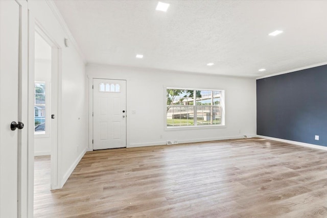 entryway featuring a textured ceiling, light hardwood / wood-style flooring, and crown molding