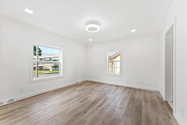 unfurnished room with a wealth of natural light, light hardwood / wood-style floors, and a textured ceiling