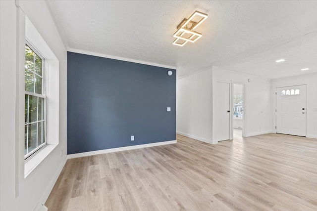 unfurnished living room with crown molding, a textured ceiling, and light hardwood / wood-style flooring