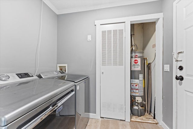 clothes washing area with light wood-type flooring, washing machine and dryer, ornamental molding, and water heater