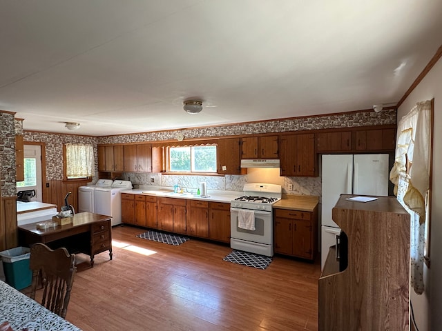 kitchen featuring sink, light wood-type flooring, white appliances, washer and dryer, and ornamental molding