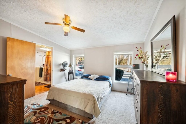 bedroom featuring ceiling fan, ornamental molding, a textured ceiling, connected bathroom, and light colored carpet