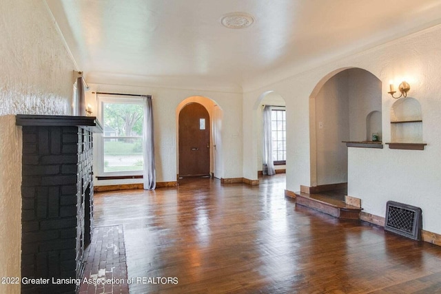 foyer entrance featuring dark hardwood / wood-style floors and a brick fireplace