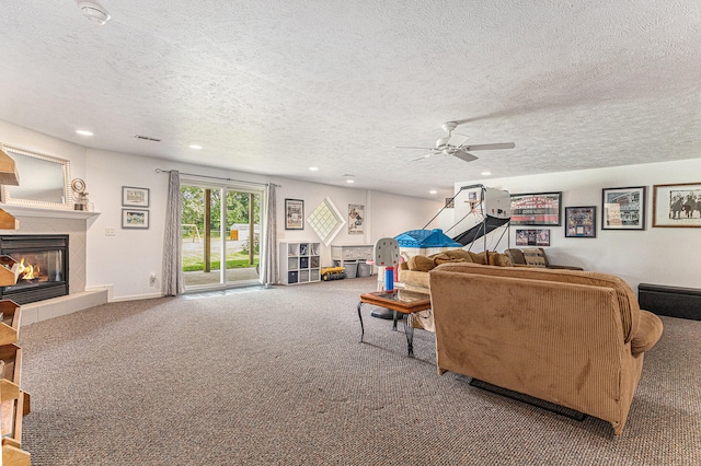 carpeted living room featuring a fireplace, ceiling fan, and a textured ceiling