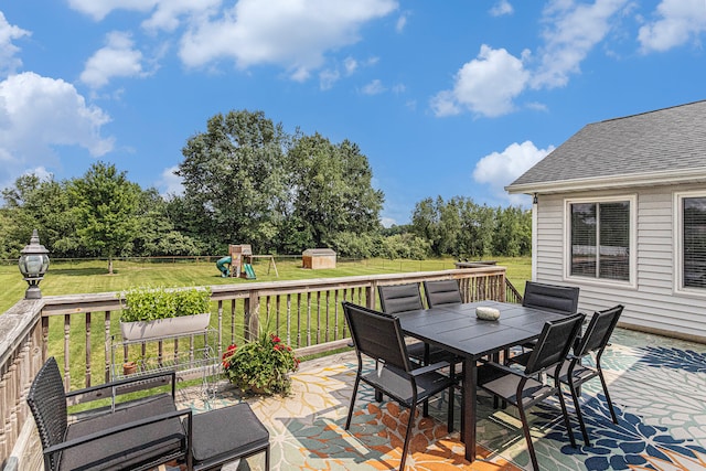 wooden deck with a yard, a playground, and a storage shed