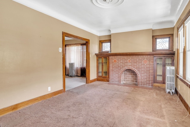 unfurnished living room with light carpet, radiator heating unit, ornamental molding, and a brick fireplace