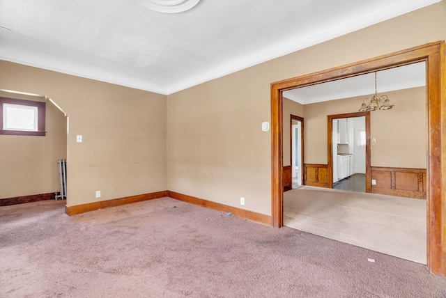 empty room featuring a notable chandelier, carpet floors, and radiator