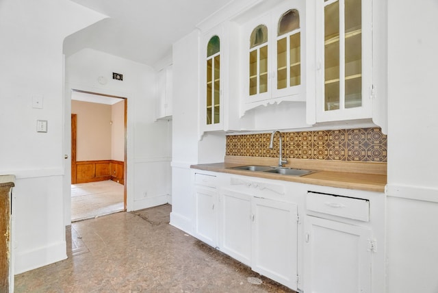 kitchen featuring white cabinets, backsplash, and sink