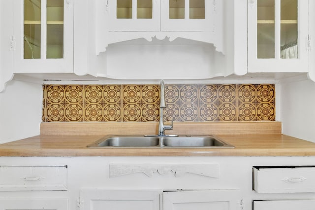 kitchen with backsplash, white cabinets, and sink