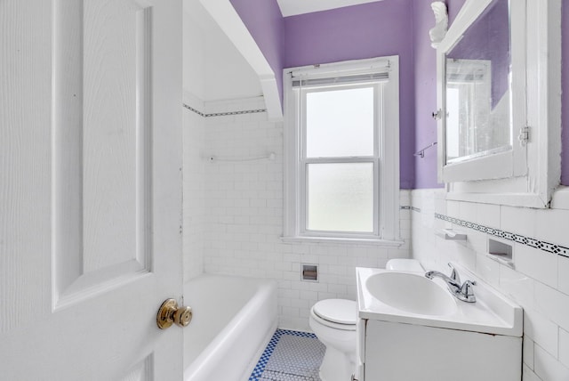 bathroom featuring tile patterned floors, a bathtub, vanity, tile walls, and toilet