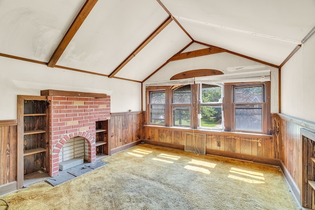 unfurnished living room featuring a fireplace, vaulted ceiling with beams, and wooden walls