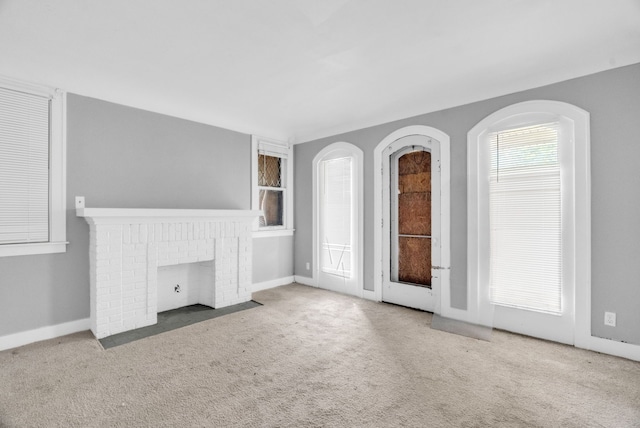 unfurnished living room featuring carpet floors and a brick fireplace