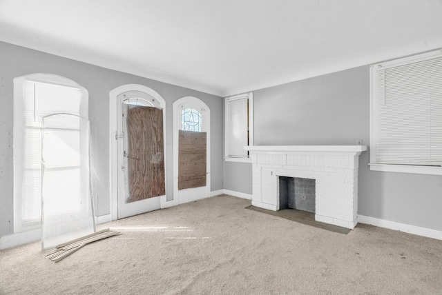 unfurnished living room featuring light colored carpet and a brick fireplace