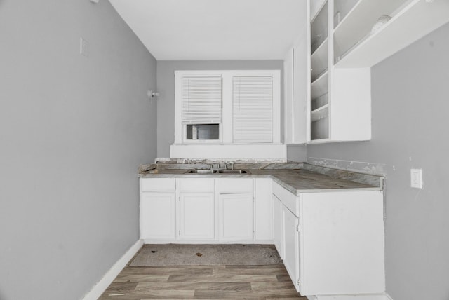 kitchen with white cabinetry, light wood-type flooring, and sink