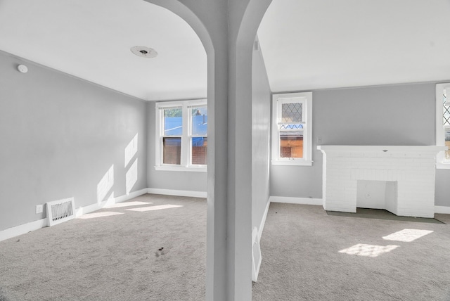 unfurnished living room featuring carpet flooring and a brick fireplace