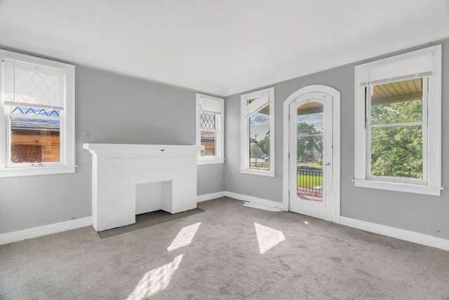 unfurnished living room with carpet and a brick fireplace