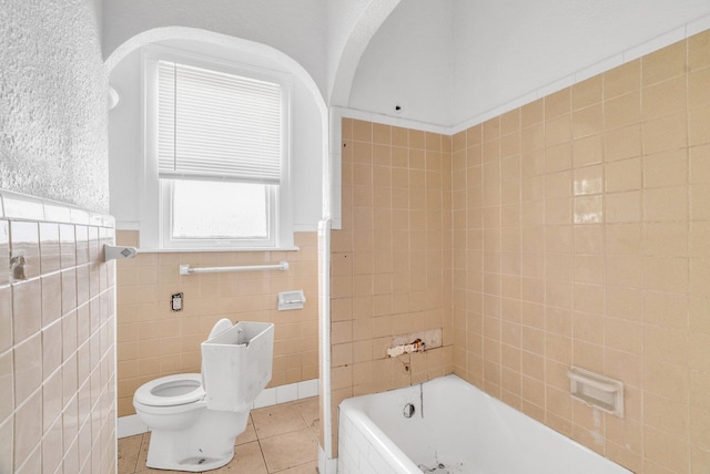 bathroom with tile patterned flooring, a bathtub, toilet, and tile walls