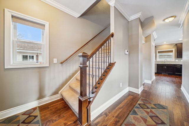 staircase with wood-type flooring, ornamental molding, and sink