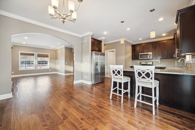 kitchen featuring crown molding, a notable chandelier, dark hardwood / wood-style floors, and appliances with stainless steel finishes