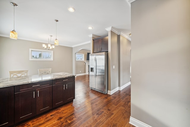 kitchen with stainless steel fridge with ice dispenser, dark hardwood / wood-style flooring, light stone counters, pendant lighting, and ornamental molding