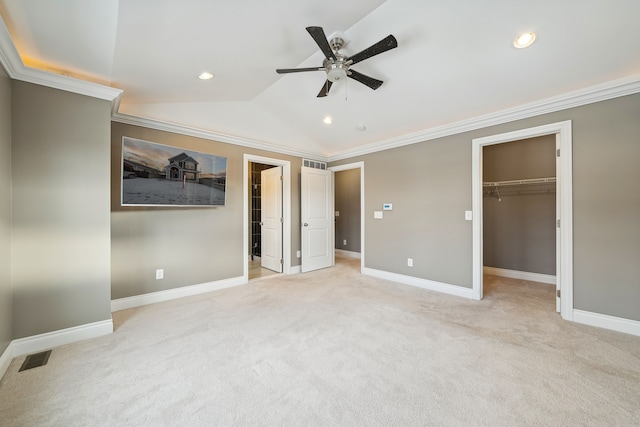 unfurnished bedroom featuring ceiling fan, vaulted ceiling, a walk in closet, a closet, and ornamental molding