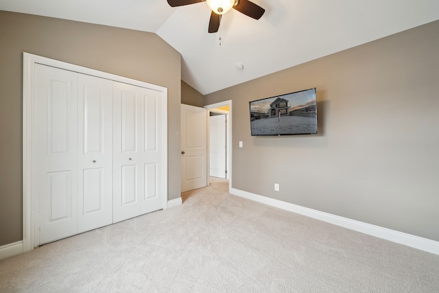 unfurnished bedroom with ceiling fan, a closet, light colored carpet, and lofted ceiling