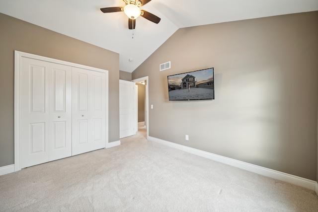 unfurnished bedroom featuring a closet, light colored carpet, vaulted ceiling, and ceiling fan