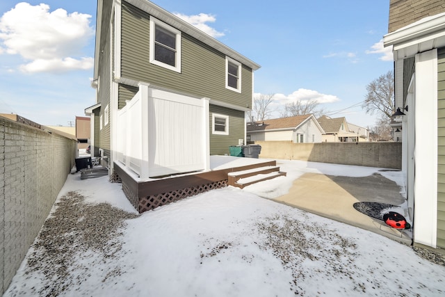 snow covered rear of property featuring central AC unit