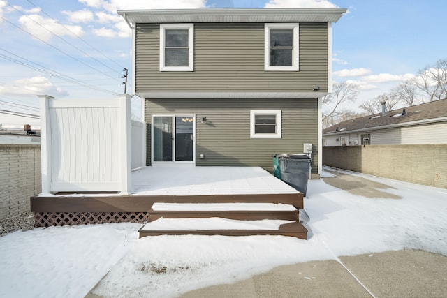 snow covered back of property featuring a deck