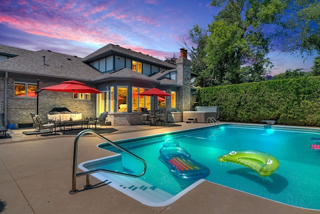 pool at dusk featuring an outdoor hangout area, a diving board, a patio, and a jacuzzi