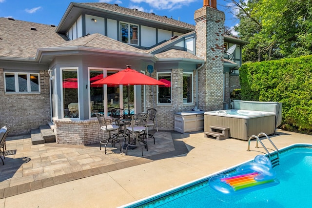 back of property with a pool with hot tub and a patio